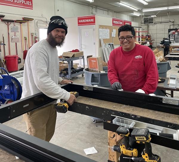 two apprentices work together on a glazing unit