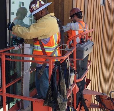 two glaziers on scaffolding installing glass