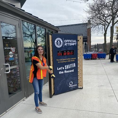 woman stands in front of a countdown sign promoting the recycling challenge